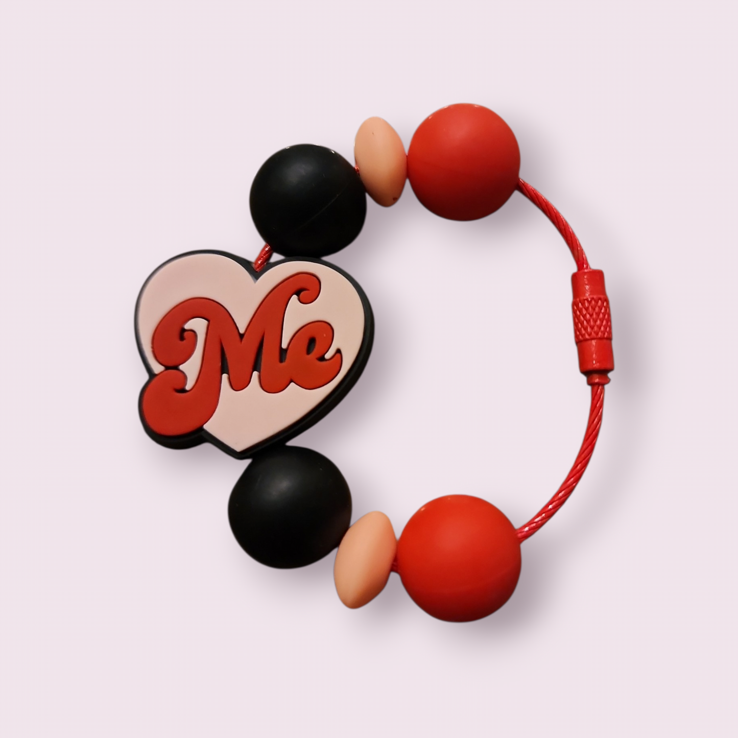 Red, black, and beige beaded bracelet with heart charm saying 'Me' on white background