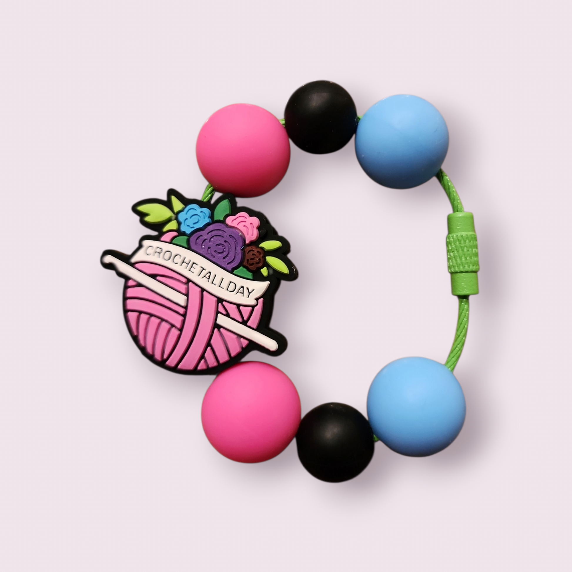 Crochet-themed silicone teething bracelet with pink, black, and blue beads and floral yarn charm