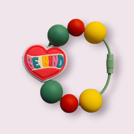Colorful beaded bracelet with heart charm saying 'BE KIND', featuring green, red, and yellow beads on a green cord.